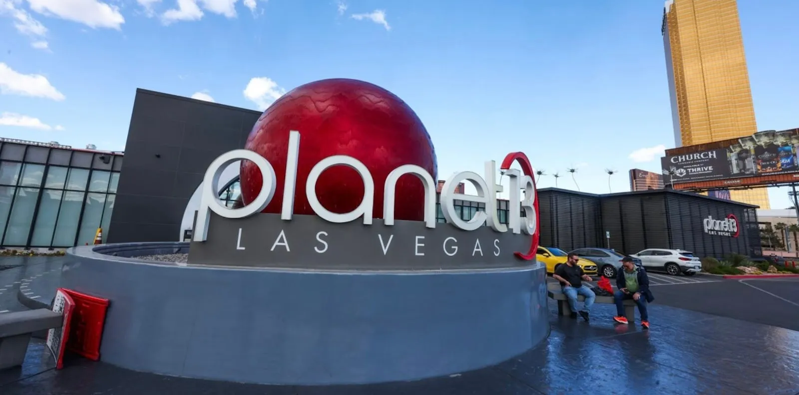 The Planet 13 Las Vegas sign and its red sphere out front, a Strip tower behind