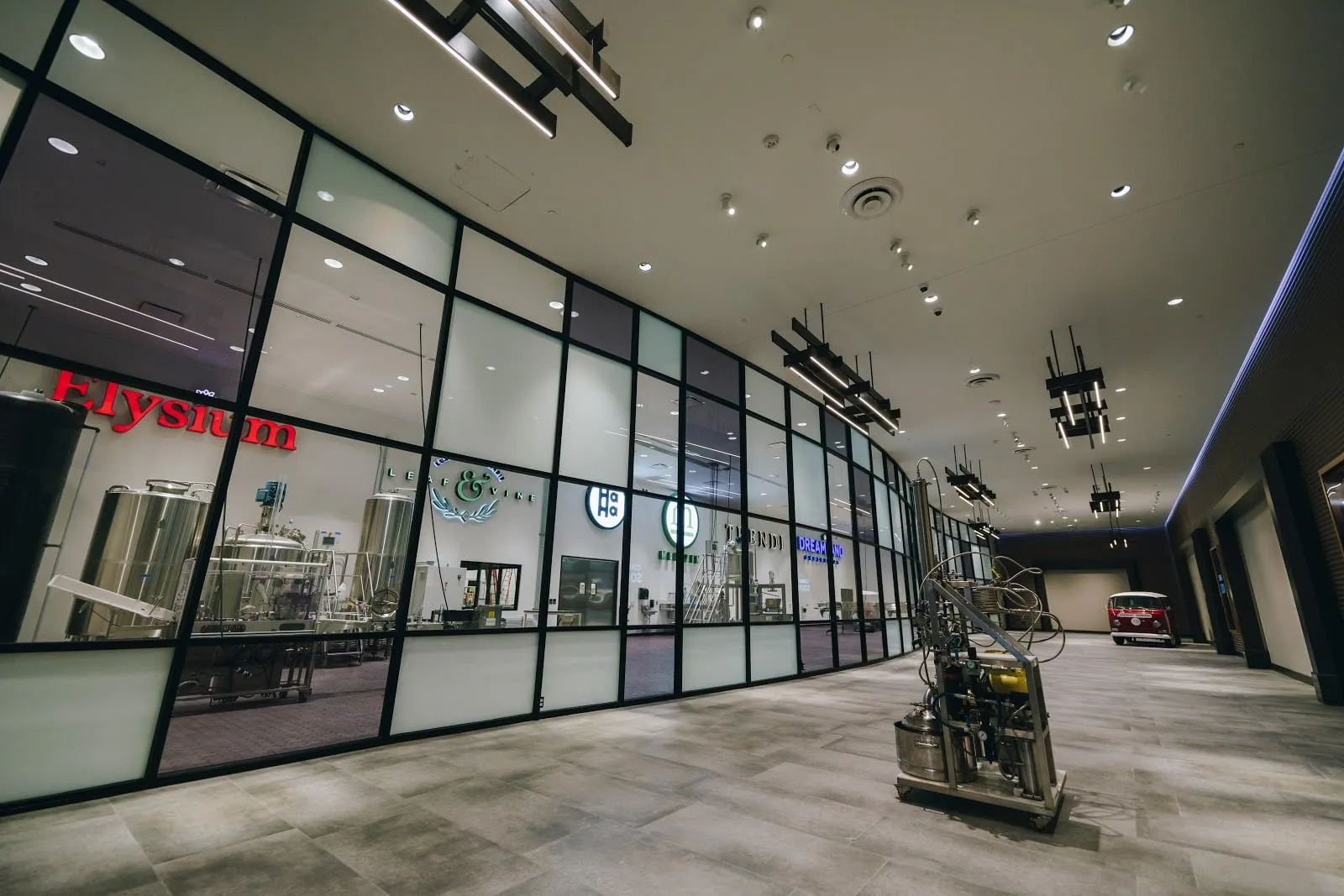 Steel tanks and brand signs on the production floor, seen through its long glass wall