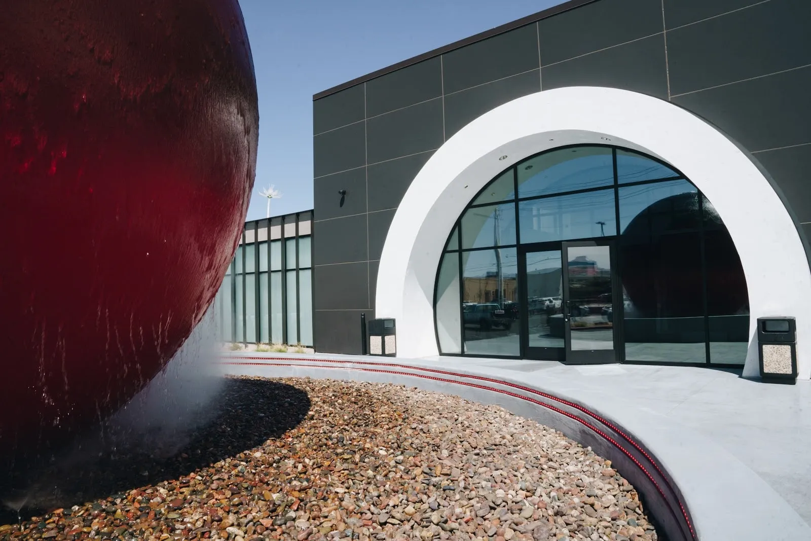The arched glass entrance beside the red sphere