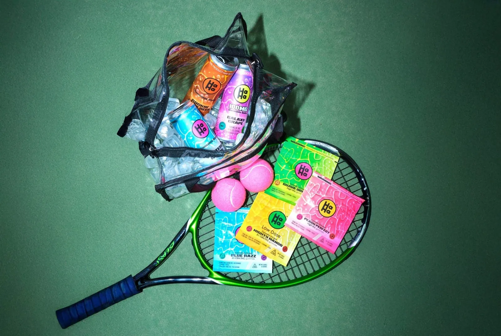 HaHa gummies and drinks in a clear bag on a tennis racket, with pink tennis balls