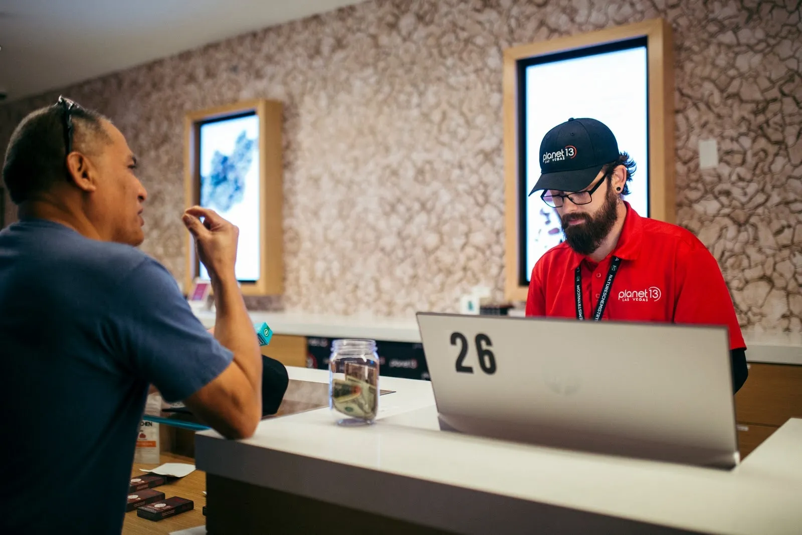 A shopper at a Planet 13 register with an associate at the counter