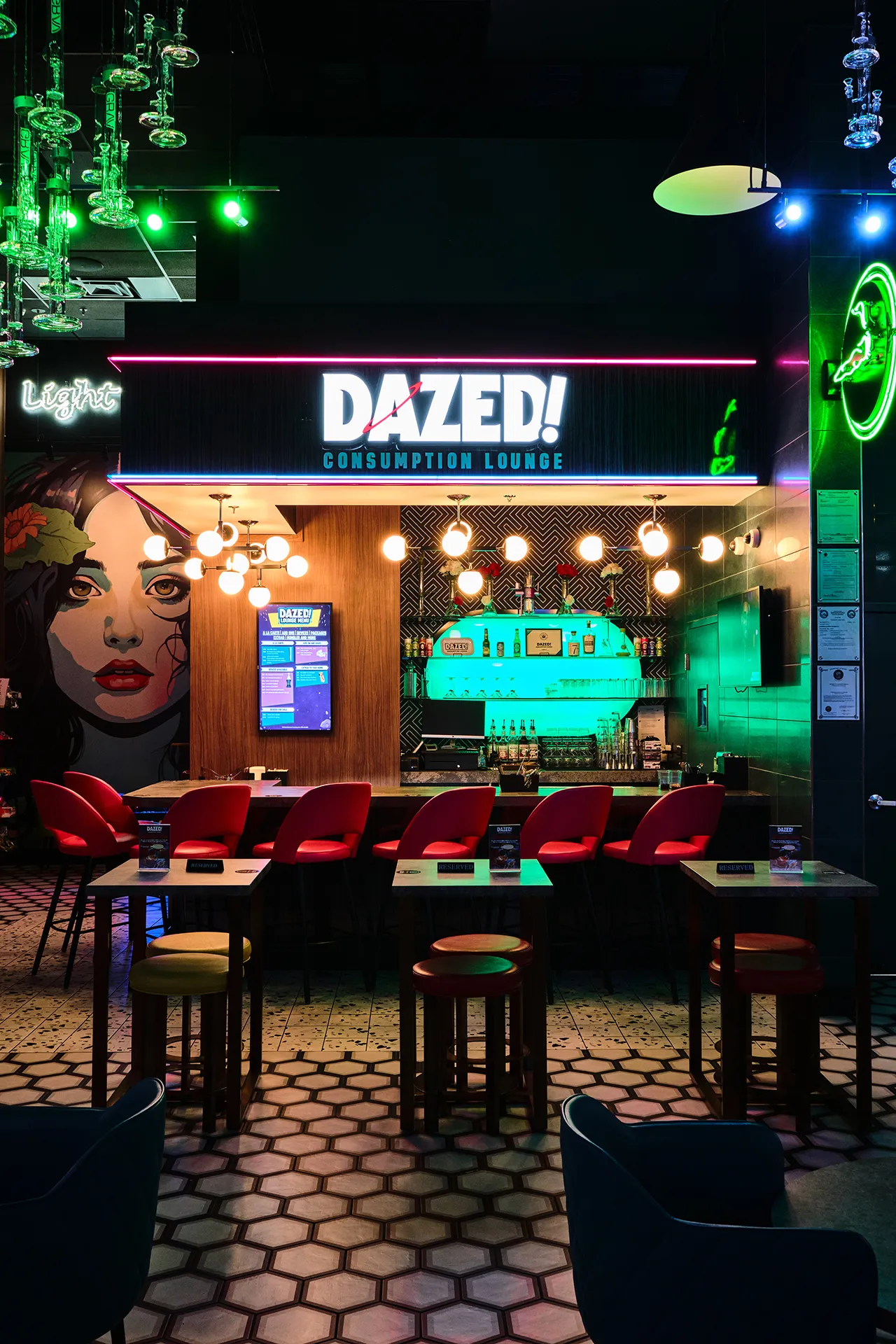 The DAZED! bar under its neon sign, red stools along the counter and a mural beside it
